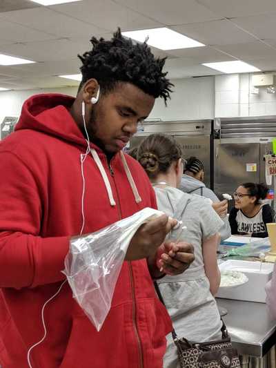 Student using a pastry bag to learn how to make buttercream roses.  