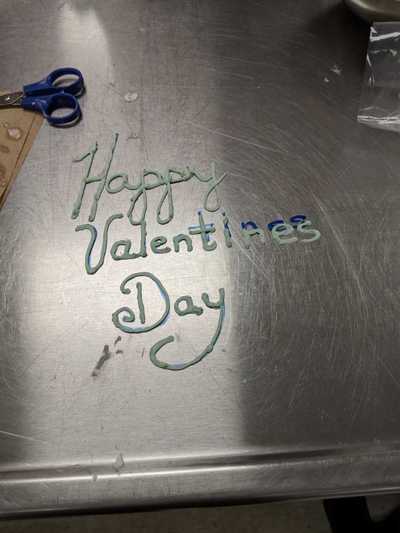 Happy Valentine's Day written with buttercream frosting on table.  