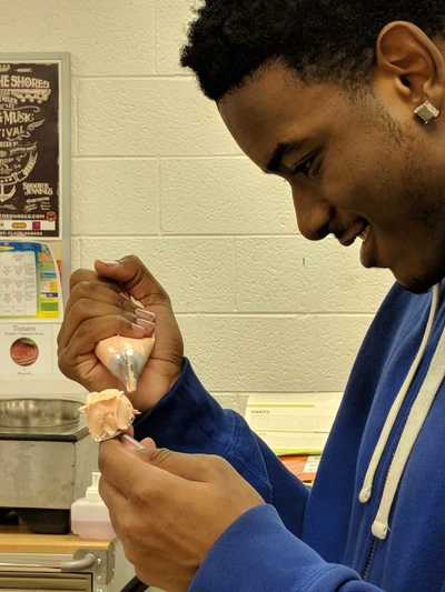 Close up of a student creating a buttercream rose.