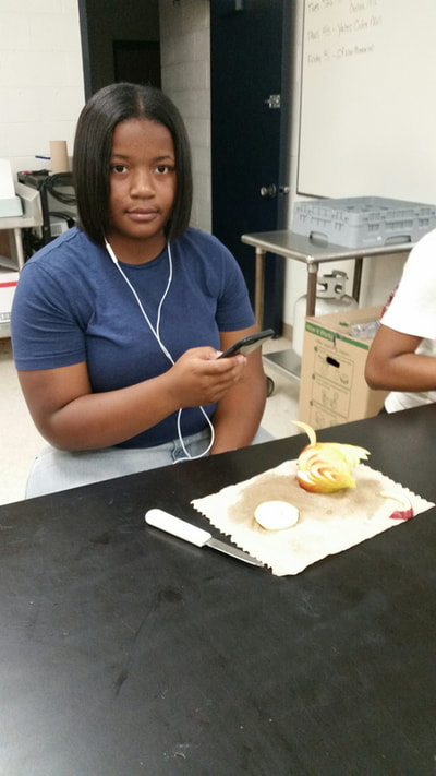 Culinary 5 and 6 student posing with completed apple swan.