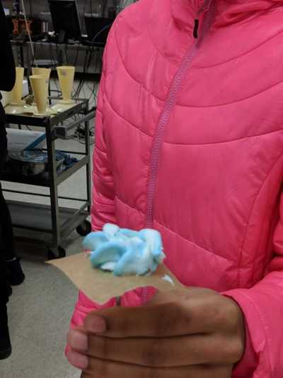 Female student displaying her blue buttercream frosting rose. 