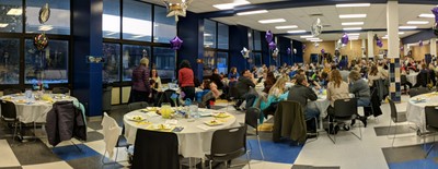 Panoramic picture of event featuring tables and people in attendance.