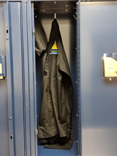 Black jacket and hat hanging in lockers in classroom.
