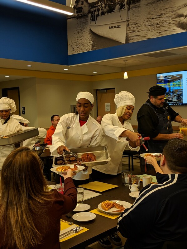 Student chefs serving breakfast to guests.