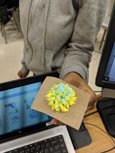 Female student displaying her blue and yellow buttercream frosting rose.  