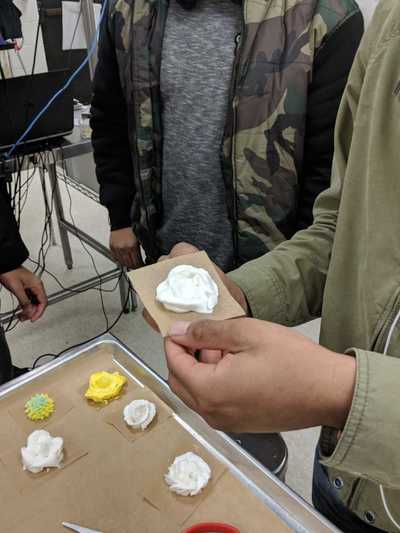 Male student displaying his white buttercream frosting rose.  