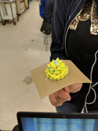 Female student displaying her yellow and blue buttercream frosting rose.