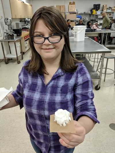 Female student in 5th and 6th hour displaying her white buttercream rose. 
