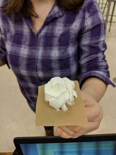 Female student in 5th and 6th hour displaying her white buttercream rose.