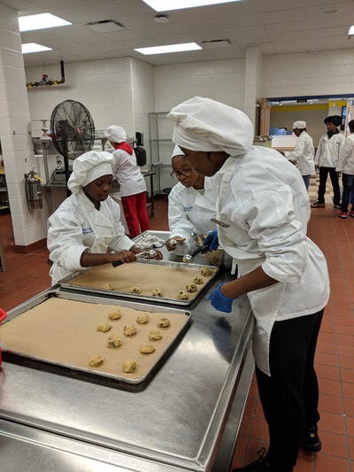 Student chefs scooping out cookie dough.