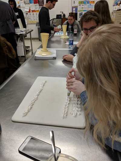 Female student practicing decorating techniques with buttercream frosting.  