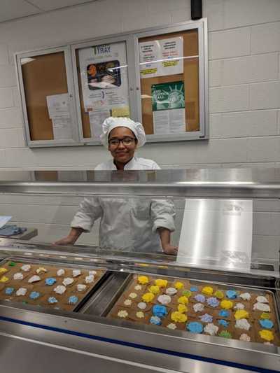 Female student chef posing in front of pre-made buttercream roses.