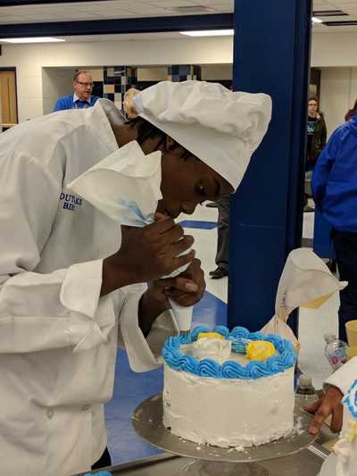 Student chef decorating cake.