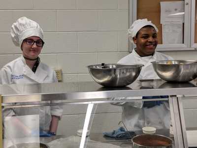 Two student chefs serving.