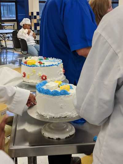Half decorated cake being attended to by a student chef.