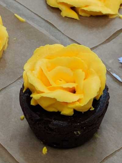 Brownie bite decorated with yellow buttercream frosting.