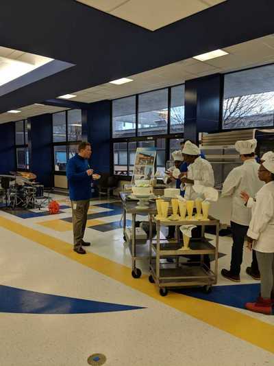 Superintendent, Mr. VonHiltmayer interacting with student chefs while they are decorating cakes.