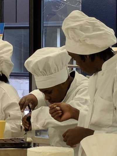 Student chefs choosing and preparing brownie bites for frosting.