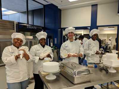Four student chefs posing with pastry bags ready to decorate.