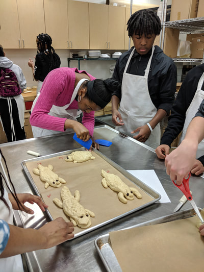 Students working on bread dough animals creating patterns and characteristics on the tops of each.  