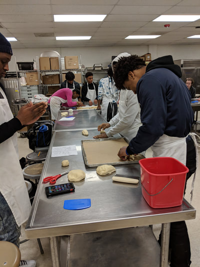 Students rolling and working bread dough into bread animals.