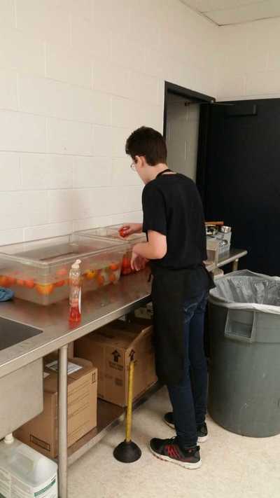 Student sanitizing tomatoes.