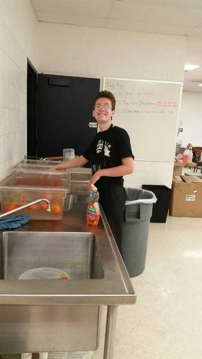 Foods student smiling while working at sink.
