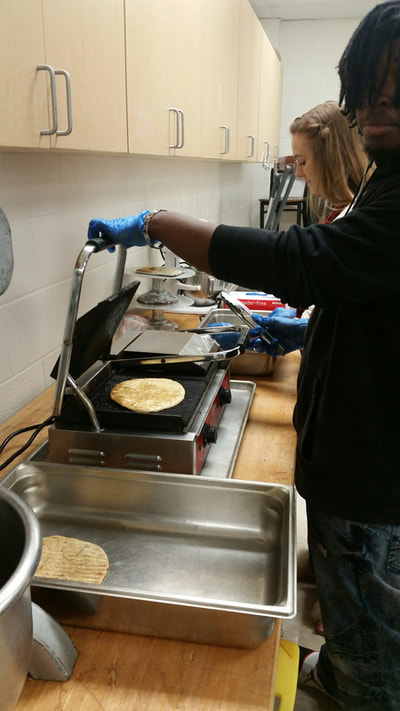 Students making fresh pita bread on the paninni press.