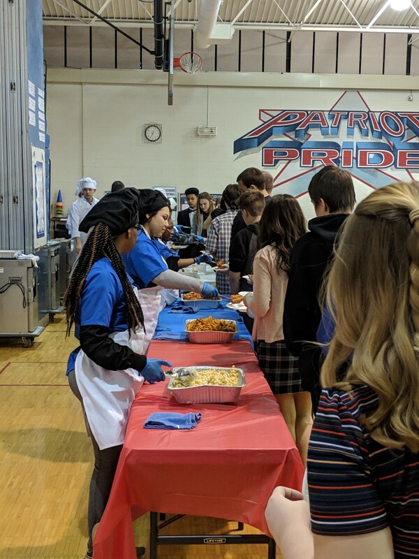 students serving a line of guests