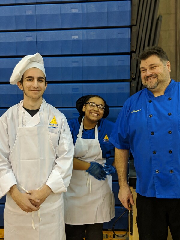 chef posing for a pic with two student chefs