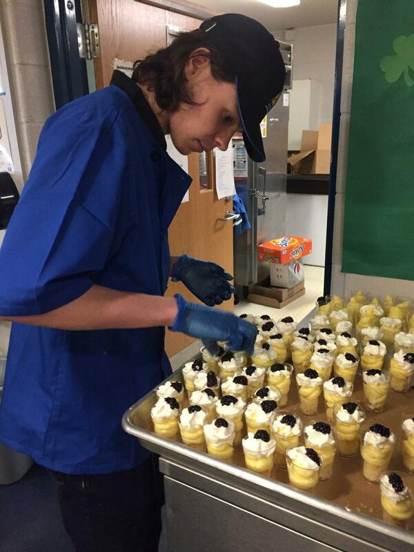 Student chef topping off desserts with banana dipped in chocolate
