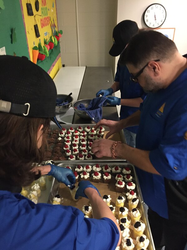 Chef Shepherd working with student chefs creating desserts
