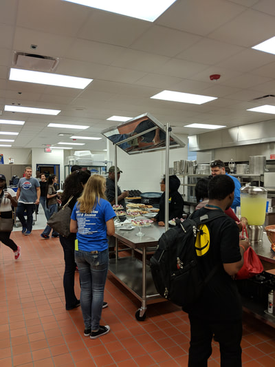 People waiting for refreshments in culinary arts kitchen.
