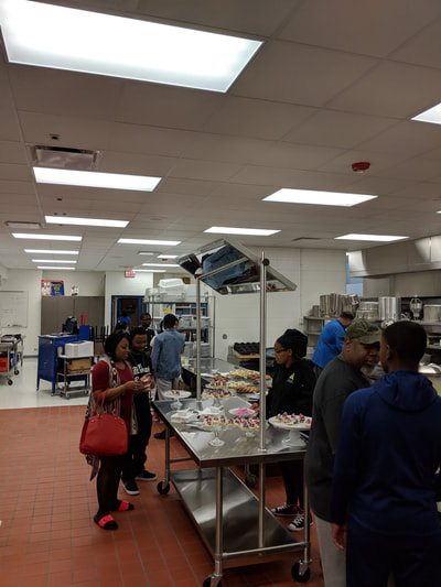 People waiting on refreshments in culinary arts kitchen.