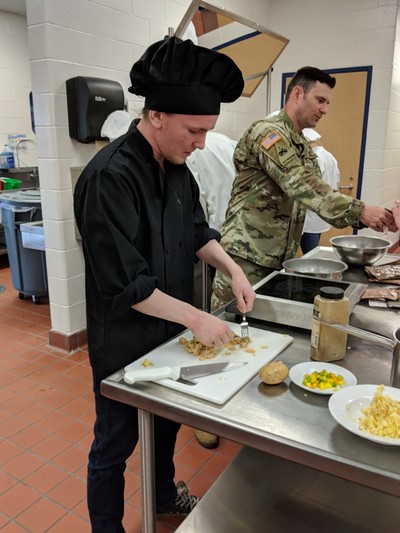 Second year student (black hat) working to create a new entree.