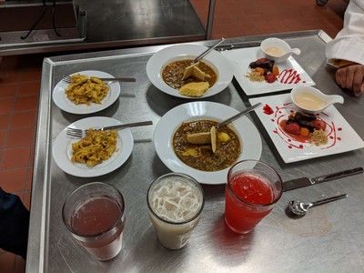A meal displayed with two entrees, two desserts, and drinks.
