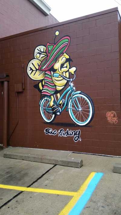 Mural of a bee riding a bike to indicate bike parking at Honey Bee Market.