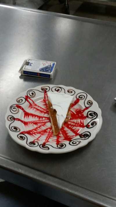 Same plate with strawberry criss crossed sauce smeared and chocolate "s"s that has a piece of pie on it
