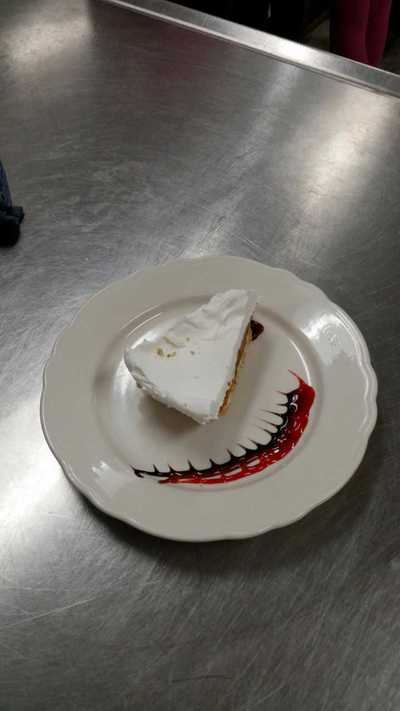 Same plate decorated with small sharklike teeth in chocolate and strawberry sauce with a piece of pie on it.