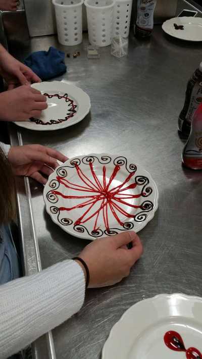 beautiful plate with strawberry sauce criss crossed and then the edges of the plate are decorated with chocolate "s"'s 