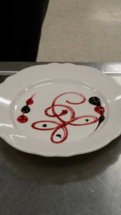 beautiful plate decorated with chocolate and strawberry sauce in a swirl similar to a butterfly and a flower combined