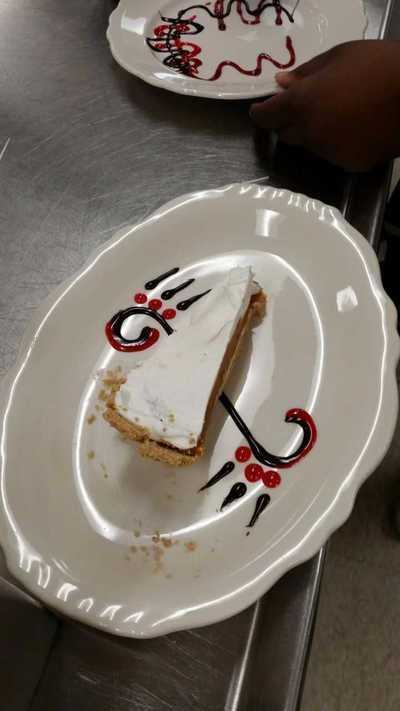 A chocolate S stretched to divide the middle of the plate with strawberry dots
on either end of the S with a piece of pie on top