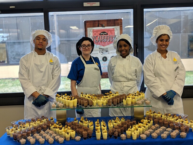 student chefs posing with dessert table