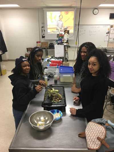 Four students cooking fried rice on a griddle.  